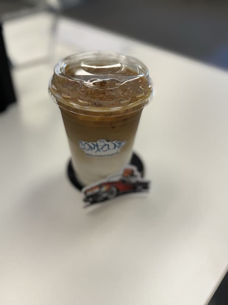 Iced latte with The Compound sticker on the cup